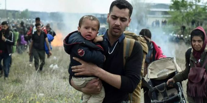 Ein Mann hält ein Baby auf dem Arm, während die Bereitschaftspolizei Tränengas einsetzt. Foto: Giannis Papanikos/AP Ein Mann hält ein Baby auf dem Arm, während die Bereitschaftspolizei Tränengas einsetzt. Foto: Giannis Papanikos/AP