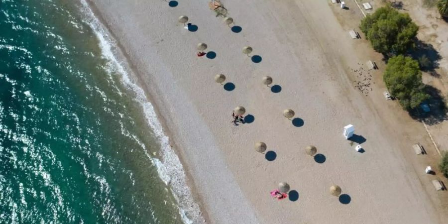 An einem Strand südlich von Athen stehen Sonnenschirme für Strandbesucher bereit. (Symbolbild). Foto: Lefteris Partsalis/XinHua/dpa