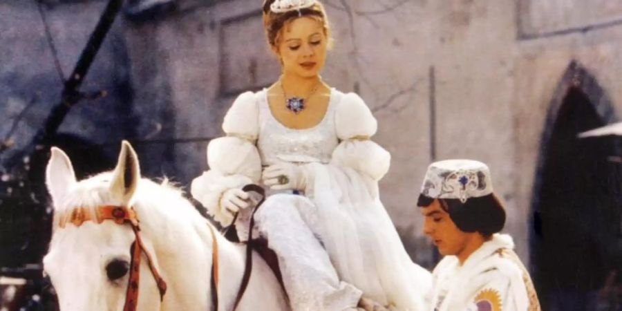 Der Prinz (Pavel Travnicek) passt Aschenbrödel (Libuse Safrankova) im Film «Drei Haselnüsse für Aschenbrödel» den verlorenen Schuh an . Foto: --/WDR/Degeto/dpa