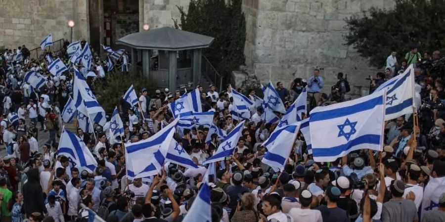 Menschen schwenken israelische Fahnen bei dem umstrittenen Flaggenmarsch in Jerusalem, der von rechtsgerichteten Nationalisten in Israel organisiert worden ist. Tausende Nationalisten zogen bei dem Marsch durch die Stadt. Foto: Ilia Yefimovich/dpa