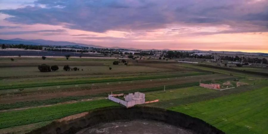 Auf einem Feld in Zentralmexiko hat sich ein grosser mit Wasser gefüllter Krater aufgetan. Das einzige Haus in der Nähe sei gefährdet. Foto: Karlos Pinpunk/dpa