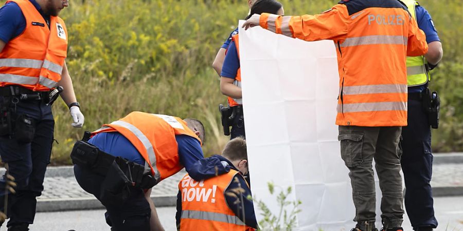 Polizeibeamte beim Entfernen eines auf die Strasse geklebten Aktivisten in Zürich. (Archivbild)