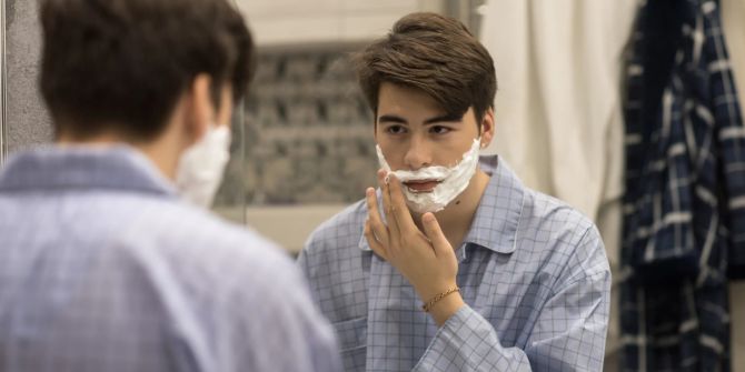 Teenager rasiert sich das Gesicht