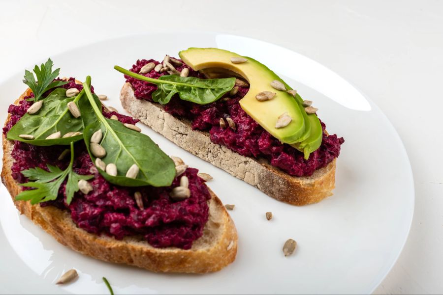 Bruschettas mit Rote-Bete-Hummus, Avocado und Spinatblättern.