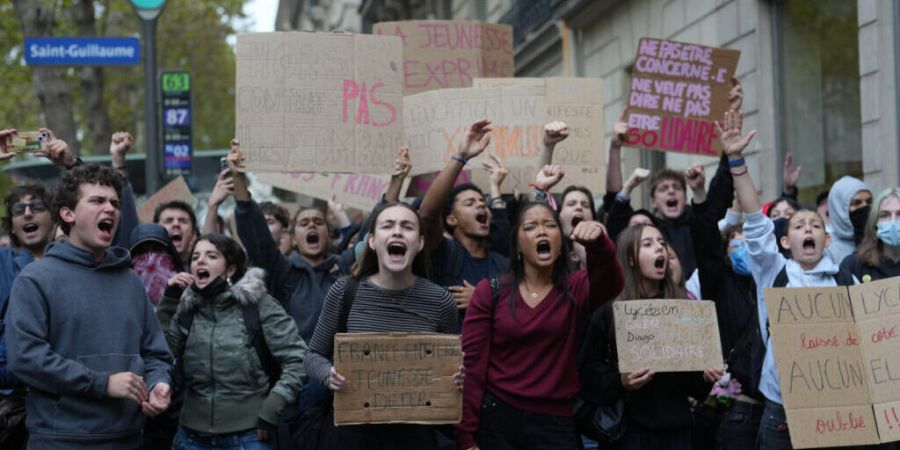 Schüler skandieren vor einem blockierten Gymnasium Parolen, um gegen die mangelnde Ausstattung der Schulen zu protestieren. Foto: Thibault Camus/AP/dpa