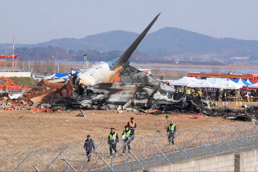 Feuerwehrleute und Rettungskräfte suchen am Wrack des verunglückten Flugzeugs auf dem internationalen Flughafen von Muan nach Opfern.