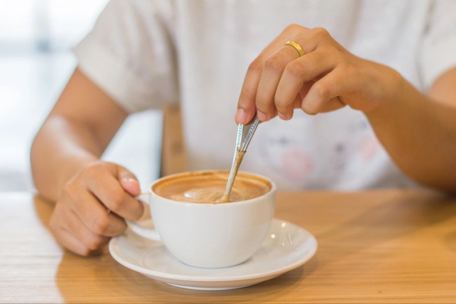 Person verrührt ihren Kaffee mit einem Löffel
