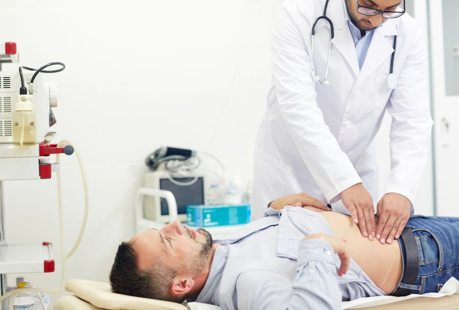Arzt tastet Bauch eines Patienten ab