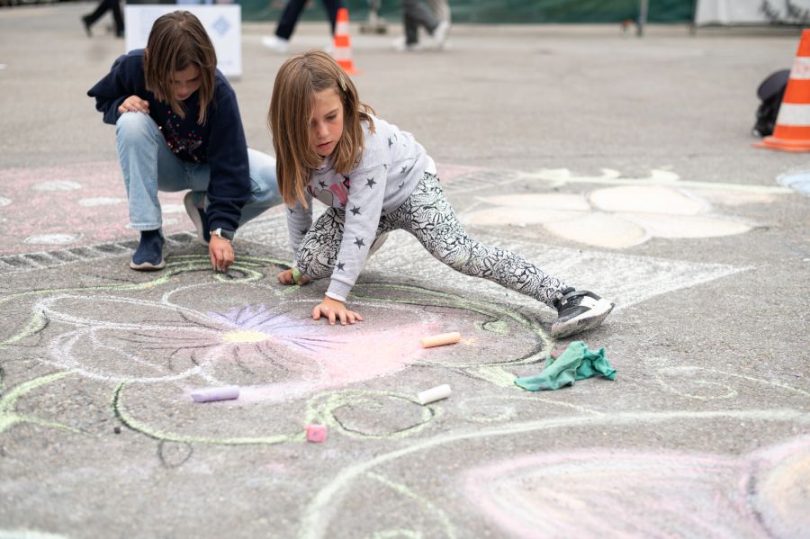 Blühende Fantasie – Mit Hingabe zeichnen Kinder farbenfrohe Blumenmotive auf den Asphalt.