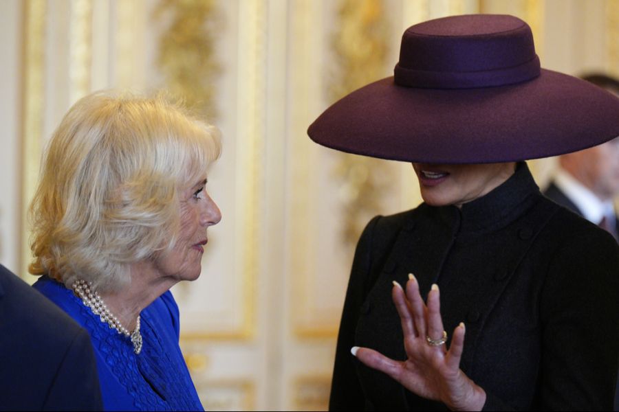Melania Trump spricht mit Camilla. Das Gesicht der First Lady wird von ihrem grossen Hut verdeckt.