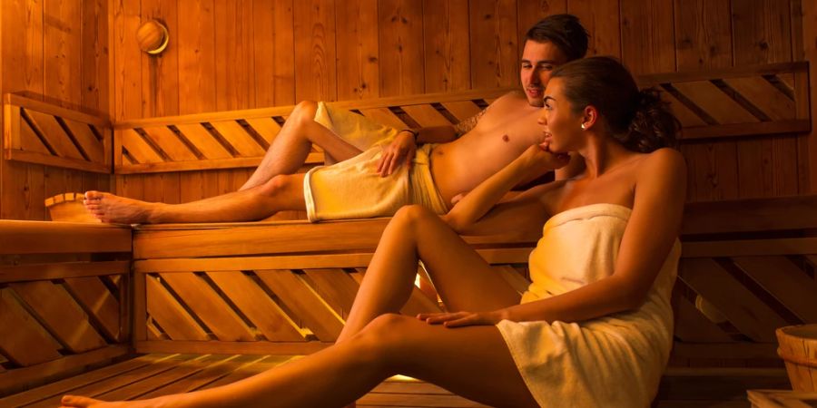 Mann und Frau mit Handtüchern bekleidet in der Sauna