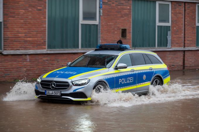 Saarland, Saarbrücken: Ein Polizeifahrzeug fährt durch die überflutete Fischbachstrasse. saarland dauerregen entwarnung