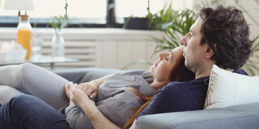 Ein entspannendes und umarmendes Paar, das auf dem Sofa liegt.