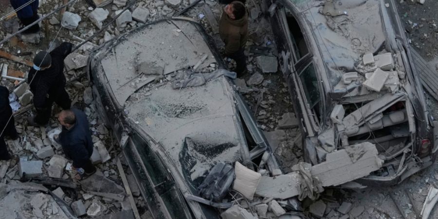 Anwohner stehen zwischen zerstörten Autos und blicken auf Wohnungen, die von israelischen Luftangriffen getroffen wurden. Foto: Hussein Malla/AP/dpa