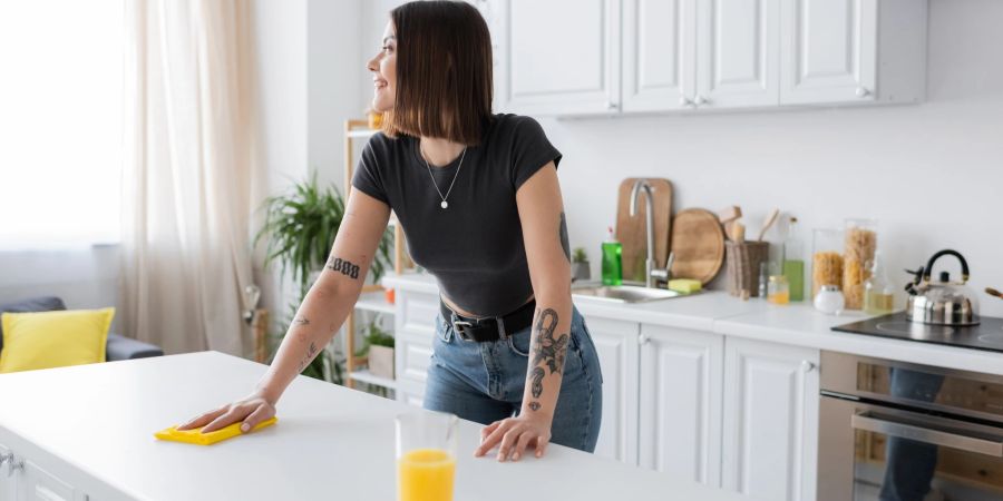 Junge Frau putzt Arbeitsplatte in Küche
