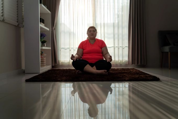 In der Meditation können Sie in sich hineinfühlen und herausfinden, warum Sie mehr essen, als ihr Köper braucht. Dicke Frau meditiert.