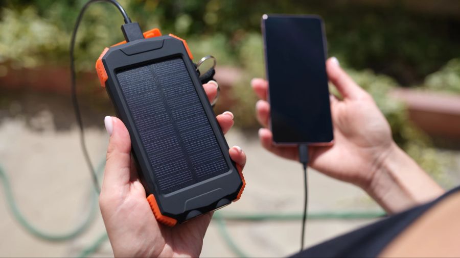 Smartphone und Solarladegerät in den Händen einer Frau