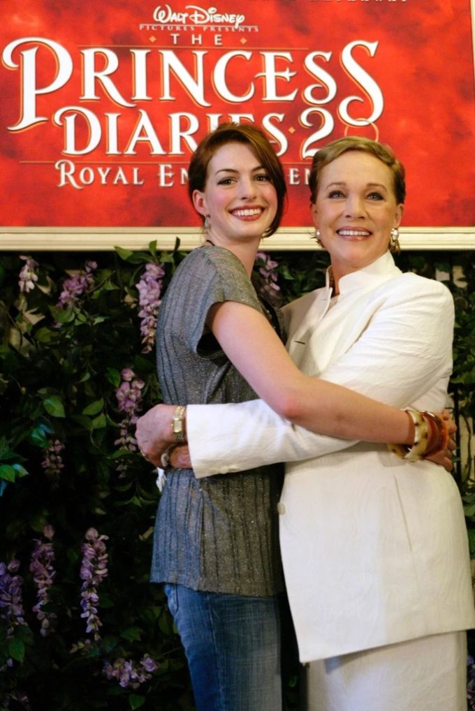 Anne Hathaway zusammen mit Julie Andrews vor einem Plakat von «Plötzlich Prinzessin 2». plötzlich prinzessin 3
