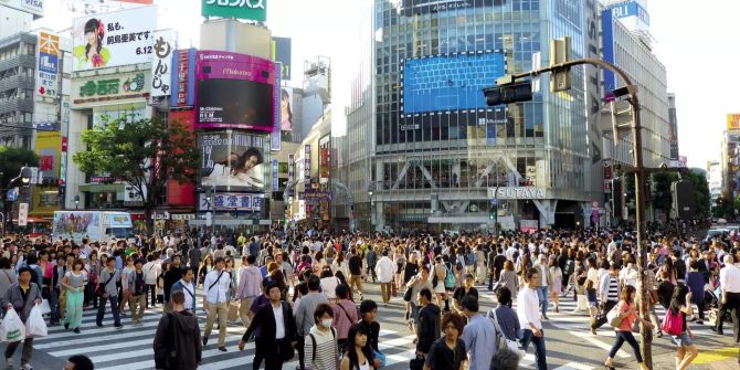 Menschen gehen über eine Kreuzung in Tokio.