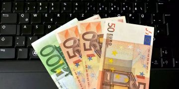 Auf einem Laptop liegen Euro-Scheine.