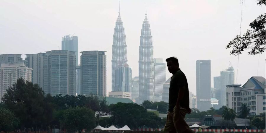 Ein Mann geht vor der Skyline mit den Petronas Towers in Malaysias Hauptstadt Kuala Lumpur.