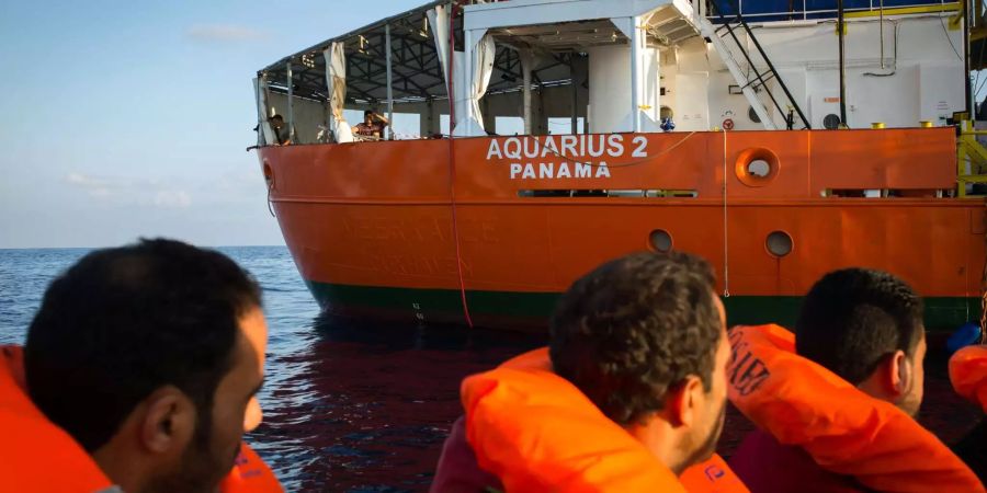 Flüchtlinge blicken von einem Boot vor der libyschen Küste aus zum Seenotrettungsschiff «Aquarius 2» der Hilfsorganisation SOS Méditerranée.