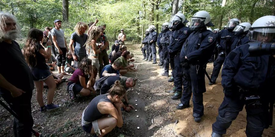 Umweltaktivisten zünden im Hambacher Forst (D) vor einer Reihe von Polizeibeamten Teelichter an.