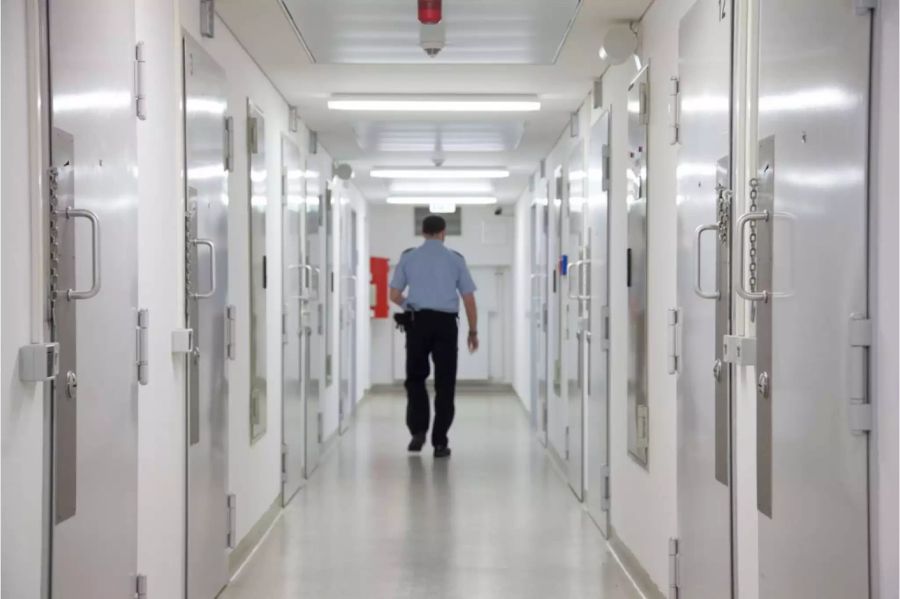 Ein Fachmann für Justizvollzug läuft durch einen Gefängnistrakt - Keystone