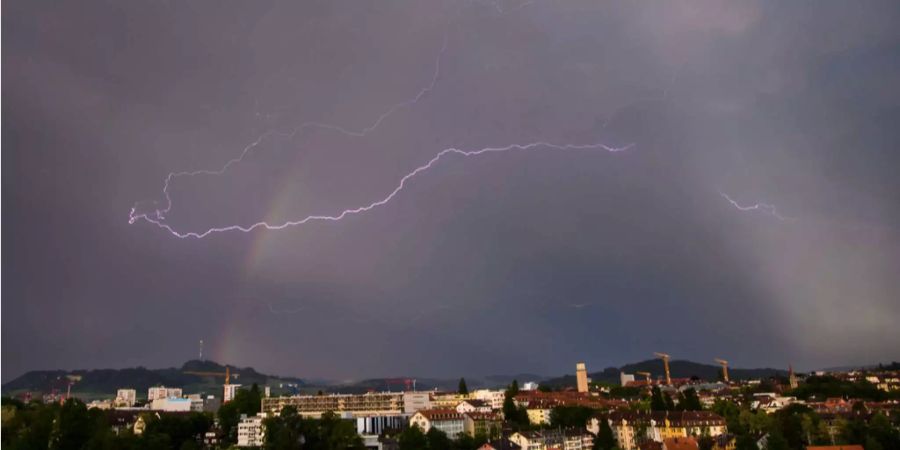 Ein Blitz ist bei einem Gewitter mit Regenbogen über der Bern zu sehen (Archivbild).