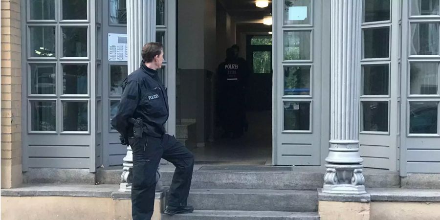 Ein Berliner Polizist steht bei einer Razzia gegen kriminelle Mitglieder arabischer Grossfamilien vor einem Haus.