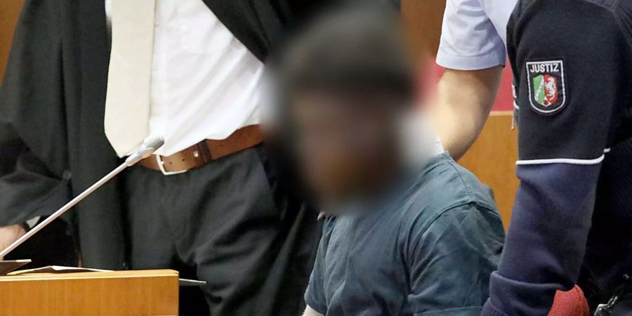 Der wegen Vergewaltigung und schwerer räuberischer Erpressung Angeklagte wird im Landgericht an Händen und Füssen gefesselt in den Saal geführt.