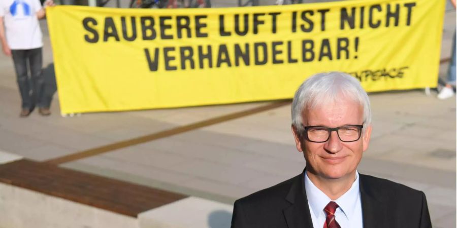 Jürgen Resch, einer der Geschäftsführer der Deutschen Umwelthilfe (DUH), steht vor Beginn der Verhandlung des Verwaltungsgerichts in Wiesbaden über ein mögliches Diesel-Fahrverbot in Frankfurt vor dem Gerichtsgebäude vor einem Greenpeace-Plakat mit der Aufschrift «Saubere».