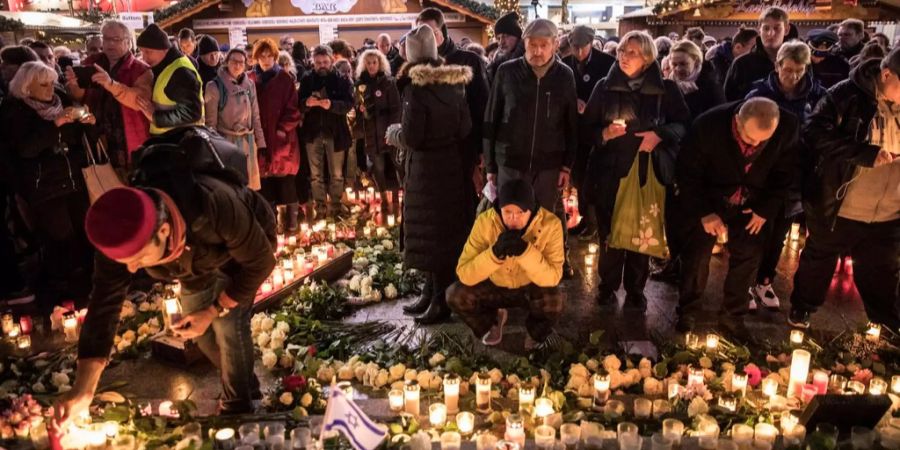 Leute gedenken Opfern des Anschlags auf einen Berliner Weihnachtsmarkt.