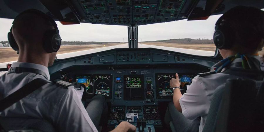 Im Cockpit eines Flugzeugs sitzt eine Pilotin und ein Copilot.