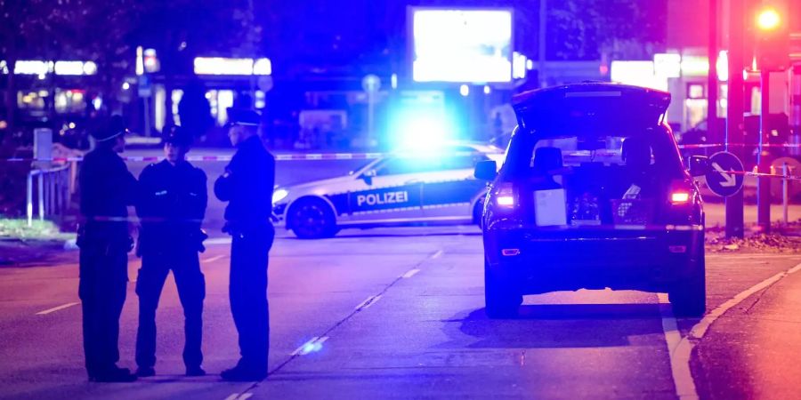 Polizisten stehen an einem mit Absperrband umgebenen schwarzem Jeep (Symbolbild).