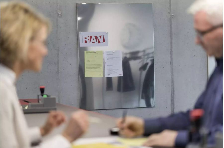 Zwei Personen sitzen zusammen in einem Büro der RAV - Keystone