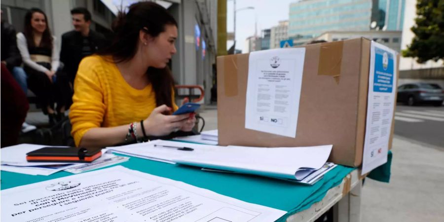 Eine Frau betreut einen Stand, an dem Anhänger der rechtspopulistischen Partei Lega über den Regierungsvertrag in Italien abstimmen sollen. Nach der Fünf-Sterne-Bewegung lässt am Wochenende auch die rechtspopulistische Lega über den Regierungsvertrag in Italien abstimmen.