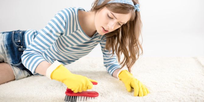 Junge Frau putzt Teppich