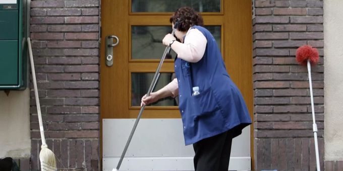 Eine Frau putzt einen Hauseingang. (Symbolbild) Putzfrau