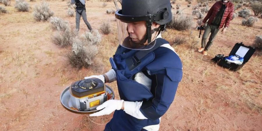 Ein Wissenschaftler hält in der Wüste des Woomera-Testgeländes für Luft- und Raumfahrt im Süden Australiens die Probenkapsel der japanischen Raumsonde «Hayabusa2». Foto: -/JAXA/AP/dpa