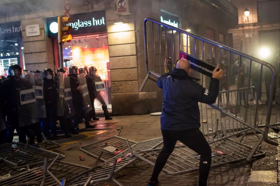 Ein Demonstrant wirft Abschrankungen gegen die Polizei.