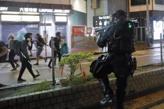 Ein Polizist richtet am Samstag seine Waffe gegen Demonstrierende. Hongkong