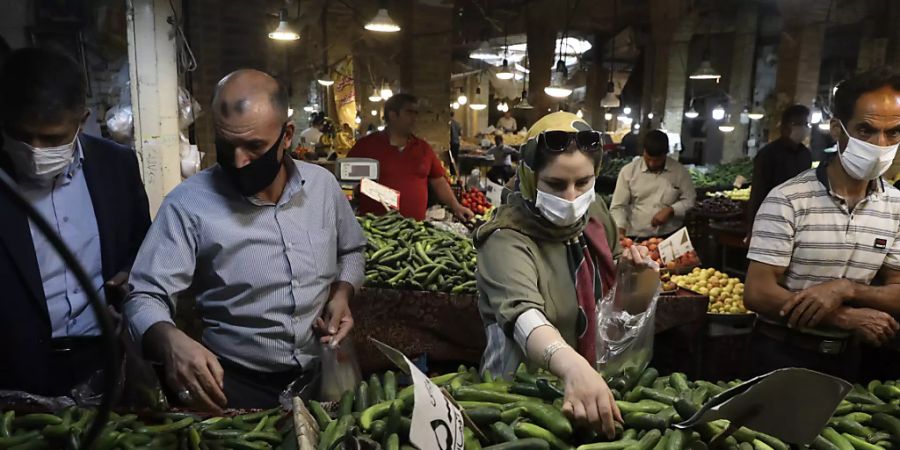Kunden mit Schutzmasken kaufen Gemüse auf dem Basar von Zandschan ein. Wegen des dramatischen Anstiegs der Anzahl der täglichen Corona-Toten und Neuinfektionen hat Präsident Ruhani eine Maskenpflicht in Behörden, im öffentlichen Nahverkehr sowie aufn überdachte Flächen von Einkaufszentren angeordnet. Foto: Vahid Salemi/AP/dpa