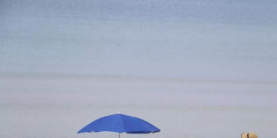 Menschen sonnen sich am Strand von Arenal auf Mallorca. Bislang dürfen aber noch keine ausländischen Touristen nach Spanien. Foto: Clara Margais/dpa