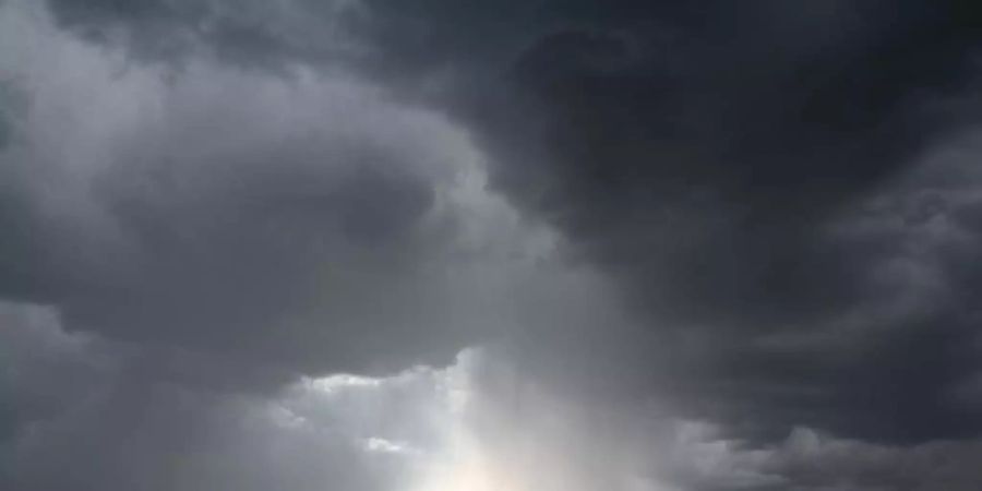 Dunkle Wolken ziehen über die Bankentürme und Hochhäuser während der Regen über der Bankenstadt einsetzt. (Archivbild). Foto: Arne Dedert/dpa