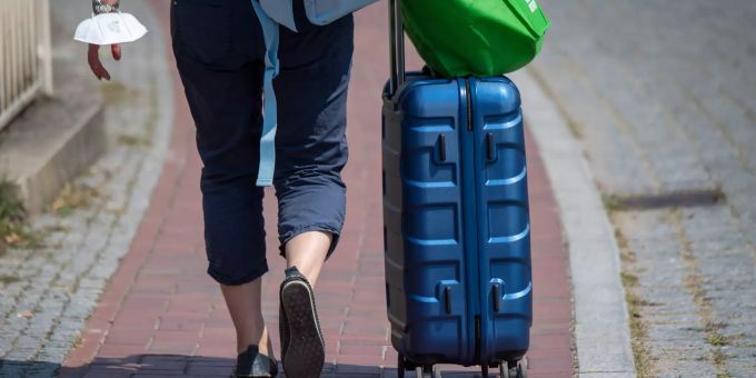 Die Koffer sind zwar noch nicht gepackt, aber durchaus einige Urlaubspläne gemacht für den Sommer 2022. zwei Beine Rollkoffer blau Fussweg Klinker