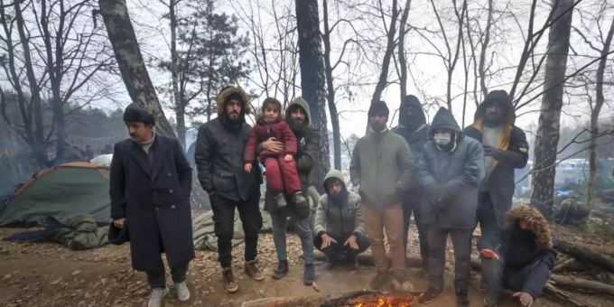 Migranten versammeln sich an der belarussisch-polnischen Grenze an einem Feuer, um sich zu wärmen. Foto: Ramil Nasibulin/BelTA/AP/dpa Migranten Polen