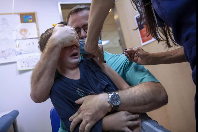 Ariel Aviran, 7, erhält seine erste Dosis des Pfizer-Vakzins, während sein Vater ihn zu beruhigen versucht. Virus Outbreak Israel