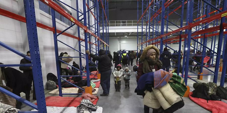 HANDOUT - Das von der belarussischen Staatsagentur BelTA via AP zur Verfügung gestellte Handout zeigt Migranten, die sich für die Nacht im Logistikzentrum am Kontrollpunkt «Kuznica» an der belarussisch-polnischen Grenze einrichten. Foto: Maxim Guchek/BelTA/AP/dpa - ACHTUNG: Nur zur redaktionellen Verwendung im Zusammenhang mit der aktuellen Berichterstattung und nur mit vollständiger Nennung des vorstehenden Credits