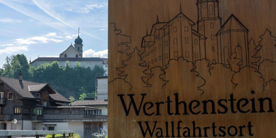 Die Ortstafel Werthenstein mit Wallfahrtskirche und Kloster Werthenstein im Hintergrund.